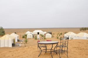 una mesa y sillas frente a tiendas en el desierto en merzouga fatima Appart hotel &Camp, en Merzouga