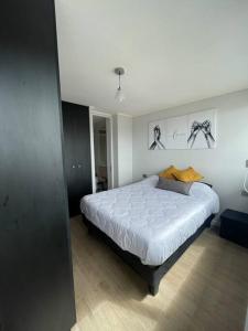 1 dormitorio con 1 cama blanca grande en una habitación en Departamento con piscina vista panorámica más estacionamiento en Coquimbo