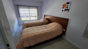 2 Betten in einem Zimmer mit einer großen braunen Couch in der Unterkunft Departamentos por día - Bartolome.gralroca in General Roca