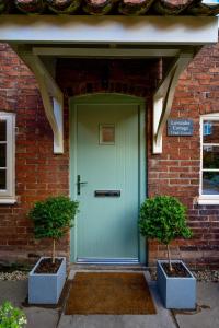a green door on a brick building with two plants at Southwell Holiday Cottage - Lavender Cottage in Southwell