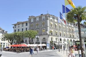 Un gran edificio con gente caminando frente a él. en Hotel Le Bourbon Pau Centre, en Pau
