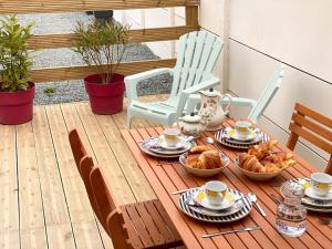 een tafel met eten en kopjes en stoelen op een patio bij L’Amazonite - Etretat in Étretat