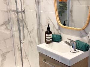 een wastafel in de badkamer met een douche en een fles zeep bij L’Amazonite - Etretat in Étretat
