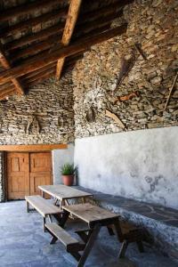 Casa Xaupí Gran في Roní: طاولتان نزهةٍ خشبيتين أمام جدارٍ حجري