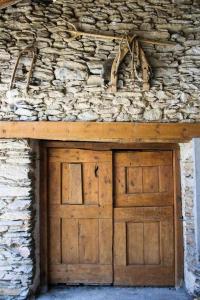 uma porta de garagem de madeira no lado de um edifício de pedra em Casa Xaupi 1 em Roní