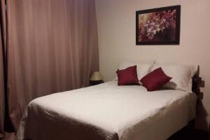 a bedroom with a white bed with two red pillows at Sitio Recanto da Paz Chalés - casa e chalé para temporada in São Pedro da Serra