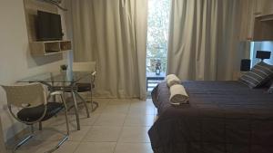 a bedroom with a bed and a table and a window at Plaza 376 in Chivilcoy