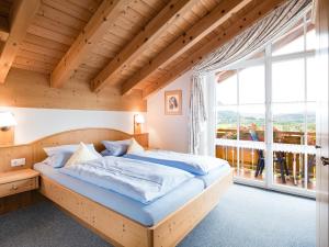 a bed in a room with a large window at Waldchalets & Ferienwohnungen Allgäu in Burgberg