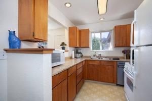 a kitchen with wooden cabinets and a white refrigerator at Convenient 2BR Walk To Bart 10 Min To Berkeley in Richmond