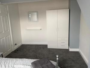 a white bedroom with a bed and a white cabinet at Cheerful 3 bedroom Townhouse in Leeds