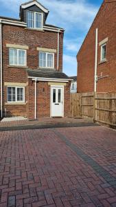 a brick house with a white door and a fence at 3-Bedroom Family Holiday Home in Skegness