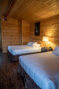 two beds in a room with wooden walls at Alaska Glacier Lodge in Palmer