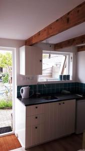 a kitchen with a sink and a window in it at Olga's Cottage in Den Helder