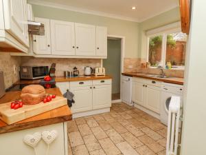a kitchen with white cabinets and tomatoes on a cutting board at Lavender Cottage, Aldeburgh in Aldeburgh +23 photos