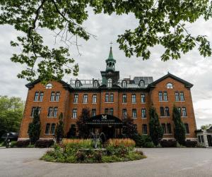 a large brick building with a clock tower on top at Hotel Montfort Nicolet in Nicolet