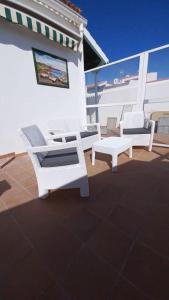 un patio con 2 sedie bianche e una panca di Casa Amanecer ad Abades