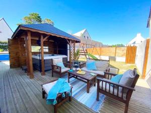 a wooden deck with a gazebo with a bed and tables at La villa Ty Mor Braz in Plouarzel