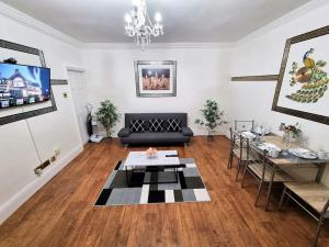 uma sala de estar com um sofá preto e uma mesa em *6B7R* Setup for your most relaxed & amazing stay + Free Parking + Free Fast WiFi* em Morley