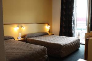 a hotel room with two beds and a window at Hôtel Florida in Lourdes +7 photos