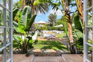 desde la ventana de un jardín con mesas y sombrillas en Villa Coloniale Schumacher Luxury Retreat en Ciudad del Cabo