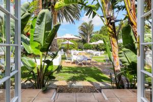 a view from a window of a garden with tables and umbrellas at Villa Coloniale Schumacher Luxury Retreat in Cape Town