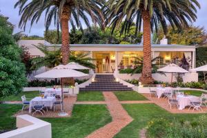 a resort with tables and chairs and palm trees at Villa Coloniale Schumacher Luxury Retreat in Cape Town