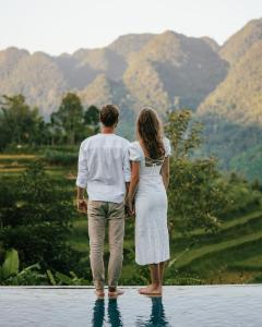 een man en vrouw die in het water staan en naar bergen kijken bij Pù Luông Ecolodge in Pu Luong