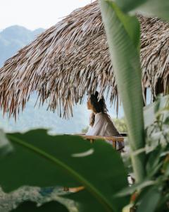 eine Frau, die unter einem strohgedeckten Regenschirm sitzt in der Unterkunft Pù Luông Ecolodge in Pu Luong