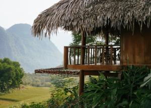 a hut with a deck and a grass roof at Pù Luông Ecolodge in Pu Luong