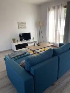 um sofá azul numa sala de estar com uma mesa em Maison Mitoyenne avec cour + parking em Sainte-Savine