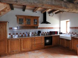 une grande cuisine avec des placards en bois et un évier dans l'établissement Maison charmante près de Nueil-les-Aubiers avec jardin, à Nueil-sous-les-Aubiers