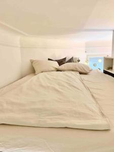 Elle comprend un grand lit blanc avec des oreillers. dans l'établissement Stylish Studio in Downtown Helsinki, à Helsinki