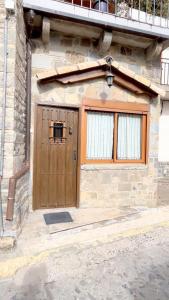 un edificio con puerta de madera y 2 ventanas en Casa Maza Apartamentos, en Biescas