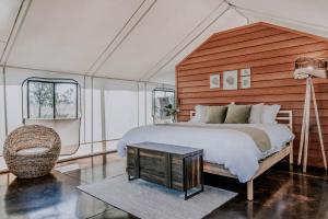 1 dormitorio con 1 cama grande y 1 silla en Salterra Glamping, en Tequisquiapan