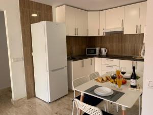 uma cozinha com uma mesa e um frigorífico branco em El Olivo House B em San Isidro