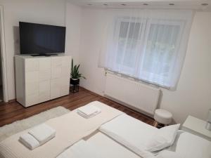 - un salon blanc avec une télévision et un canapé dans l'établissement Mátrix apartman, à Békéscsaba