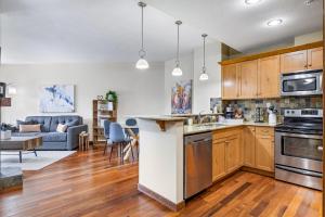a kitchen with wooden cabinets and a living room at Alluring Mountain View Condo -Right In The Heart Of Downtown!! Hosted by Fenwick Vacation Rentals in Canmore