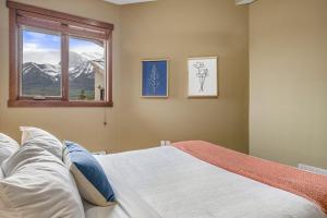 a bedroom with a bed and a window and mountains at Alluring Mountain View Condo -Right In The Heart Of Downtown!! Hosted by Fenwick Vacation Rentals in Canmore