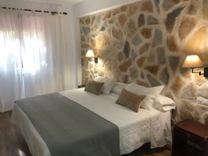 a bedroom with a large bed with a stone wall at Hotel Barbacedo in Mijares