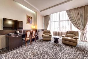 a hotel room with chairs and a flat screen tv at Terra Nova Sport&Spa Hotel in Hatne