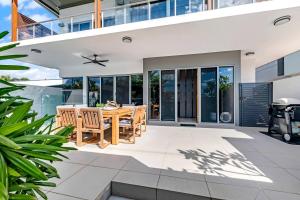 an outdoor patio with a wooden table and chairs at Poolside Gunya Luxury Living in Fannie Bay in Fannie Bay