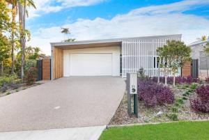 une maison avec un garage et des palmiers dans l'établissement A Sumptuous Poolside Family Oasis at Gardens Villa, à Stuart Park