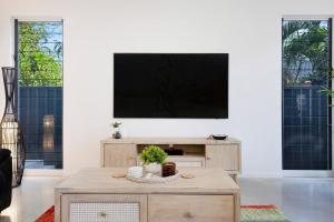 - un salon avec une télévision sur un mur blanc dans l'établissement A Sumptuous Poolside Family Oasis at Gardens Villa, à Stuart Park