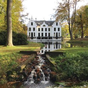 a white house with a waterfall in front of a river at RiemersHof in Ermelo