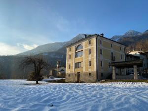 a building in the snow with mountains in the background at Sassiglioni Vacanze in Sassiglioni