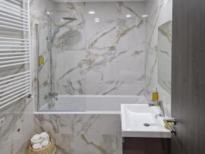 a white bathroom with a tub and a sink at Royal Maison Apartments in Cluj-Napoca +27 photos