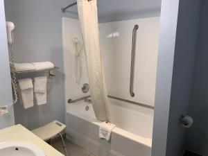 a bathroom with a tub and a toilet and a shower at Super 8 by Wyndham Eau Claire I-94 in Eau Claire +16 photos