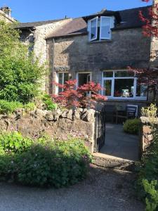 uma casa de pedra com uma parede de pedra e um pátio em Mews Cottage Arnside - 2 Bedroom Cottage em Arnside