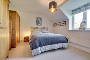 a bedroom with a bed with a blue blanket and a window at Mews Cottage Arnside - 2 Bedroom Cottage in Arnside
