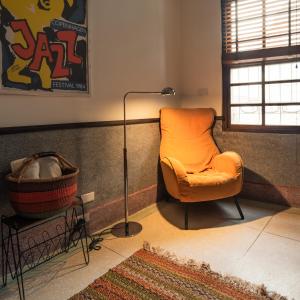 an orange chair in a room with a floor lamp at OrigInn Space in Taipei